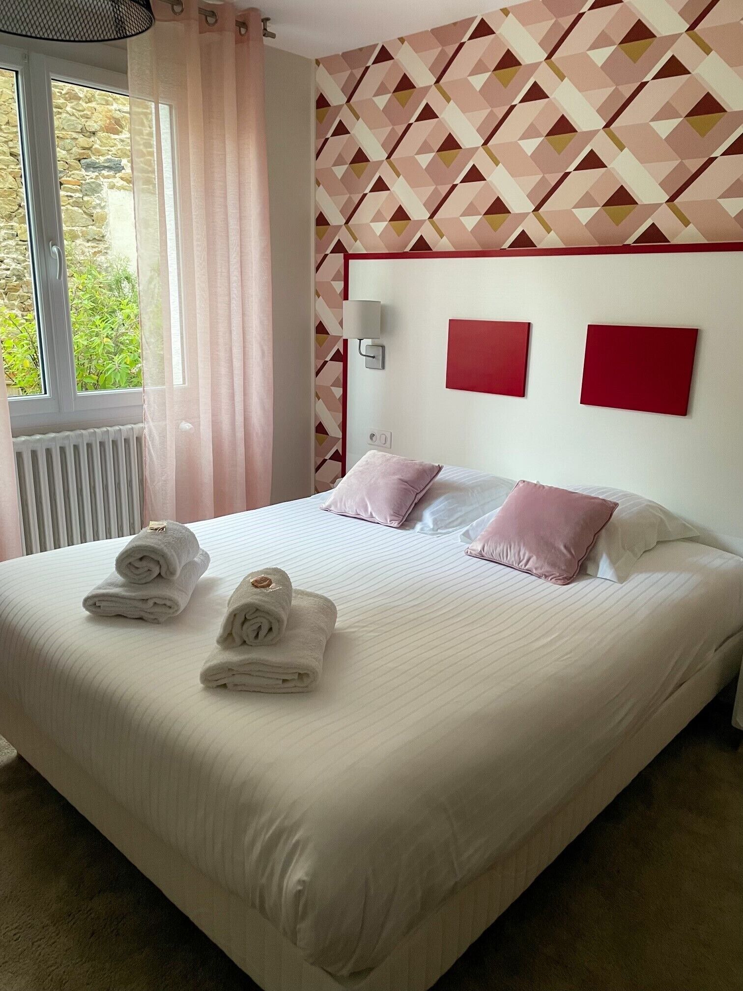 Una habitación de hotel con cama, almohadas y toallas enrolladas.