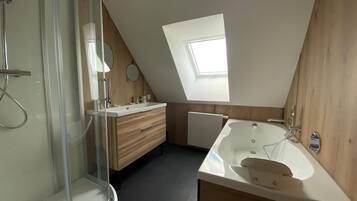 Un baño moderno con tragaluz, ducha a ras de suelo, bañera independiente y muebles de madera.