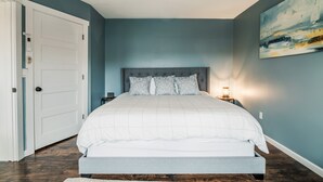 Un dormitorio con una cama, una mesita de noche, una lámpara de pared y una puerta con cerradura.