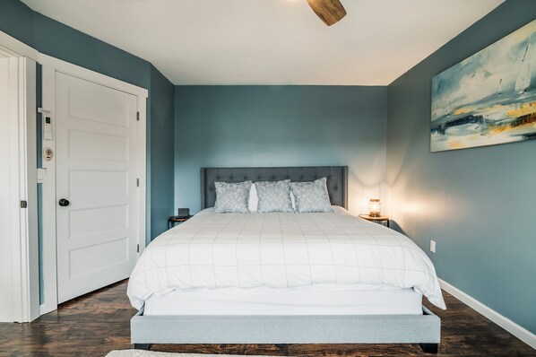A bedroom with a bed, a nightstand, a wall-mounted light, and a door with a lock.