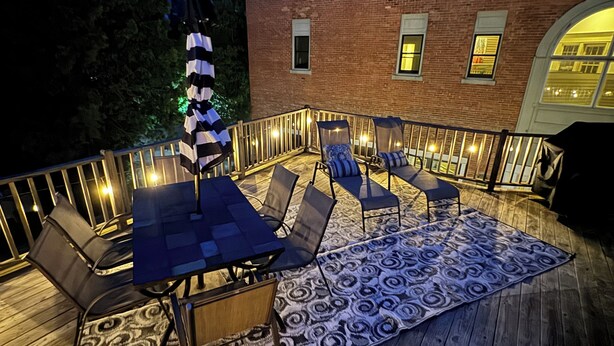 Una terraza al aire libre con una mesa y sillas, un tapete estampado y una guirnalda de luces.