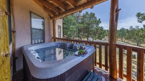A hot tub with a glass top, surrounded by wooden deck and railing, overlooking a wooded area. - White Mountain Retreat by Ruidoso Vacation Rentals (Ruidoso)