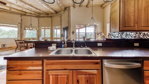 A spacious kitchen with wooden cabinets, a double sink, and pendant lighting. - White Mountain Retreat by Ruidoso Vacation Rentals (Ruidoso)