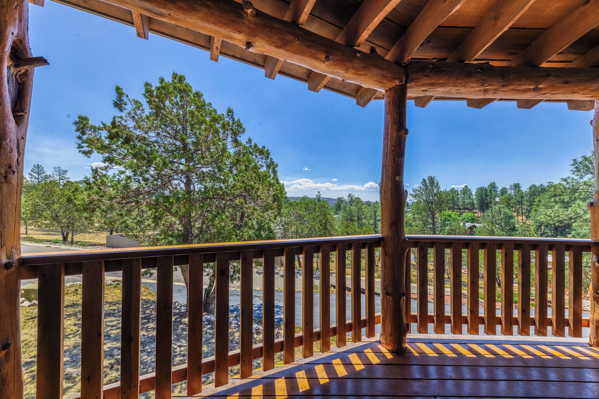 A wooden deck with a view of a forest and a clear sky.