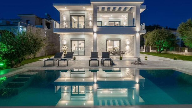 A modern two-story house with a swimming pool in the foreground.