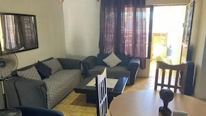 Una sala de estar con sofá, dos sillones, una mesa de centro y una mesa de comedor con sillas.