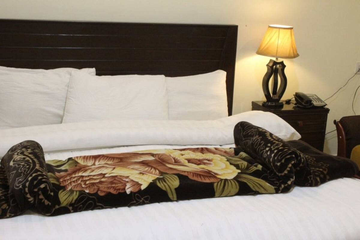 A neatly made bed with white linens, a floral-patterned blanket, and a dark headboard.