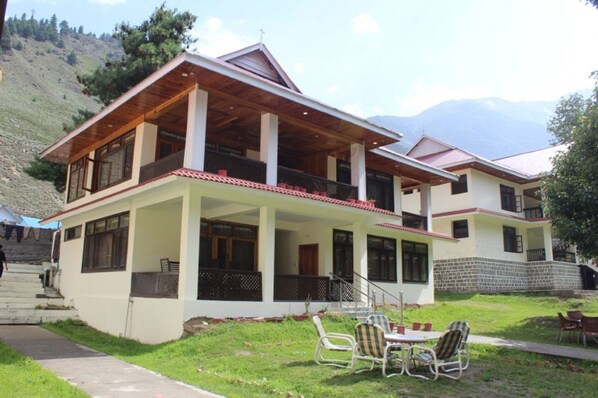 A two-story house with a balcony, a covered porch, and a small outdoor seating area.