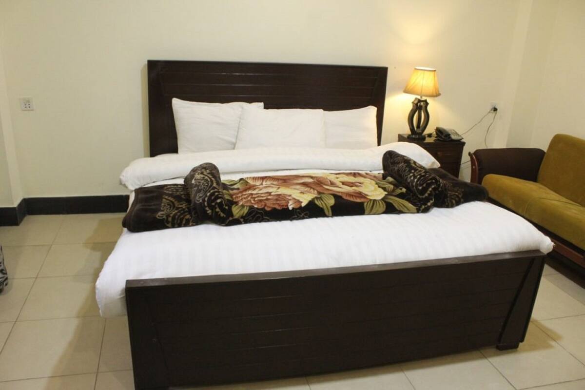 A bed with a floral bedspread, white pillows, and a dark headboard.
