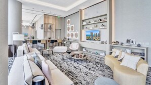 A modern living room with a sofa, armchairs, a coffee table, and a TV. There is a dining area with chairs and a table in the background. - OCEAN VIEW 2BD-2BA CONDO 2207 (Hollywood)