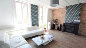 Uma sala de estar com um sofá branco, uma mesa de centro, uma lareira e uma parede de tijolos.