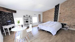 Quarto moderno com uma cama grande, uma mesa de jantar com cadeiras, uma televisão e um portão decorativo.