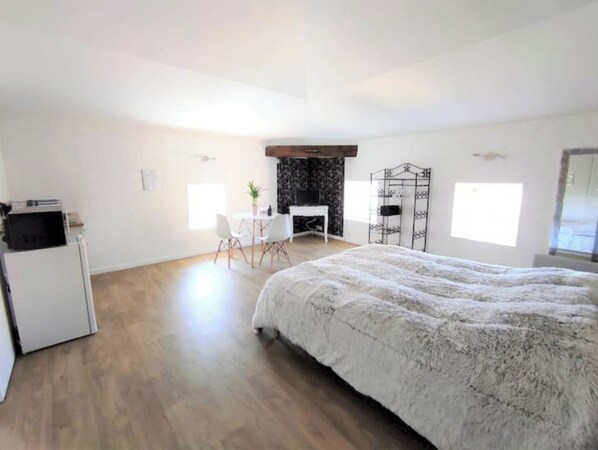 A spacious bedroom with a large bed, a desk, and a chair.