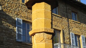 A stone pillar with a cross on top, part of a building with stone walls and blue shutters. - Apartment “Bagnols” in Theizé with sauna (Theizé)