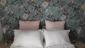 A bed with white bedding, two nightstands, and a floral wallpaper background. - Apartment “Bagnols” in Theizé with sauna (Theizé)