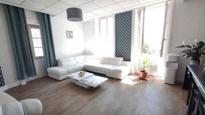 Ein modernes Wohnzimmer mit einem Ecksofa, einem Couchtisch und einer Topfpflanze.