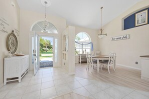 A spacious dining area with a large table and chairs, a chandelier, and a view of the outdoors. - Dock Holliday by Ryson Vacation Rentals (Palm Coast)