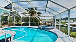 A covered swimming pool with a hot tub, surrounded by palm trees and a clear sky. - Dock Holliday by Ryson Vacation Rentals (Palm Coast)