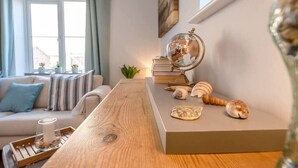 Ein gemütlicher Wohnbereich mit einem Holztisch, einem Globus, Büchern und dekorativen Muscheln.