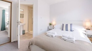 Ein modernes Schlafzimmer mit einem großen Bett, Nachttischen und einem sichtbaren Badezimmer.