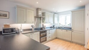 A modern kitchen with light-colored cabinets, a dark countertop, and stainless steel appliances. - Rest Ashored, Aldeburgh (Aldeburgh)