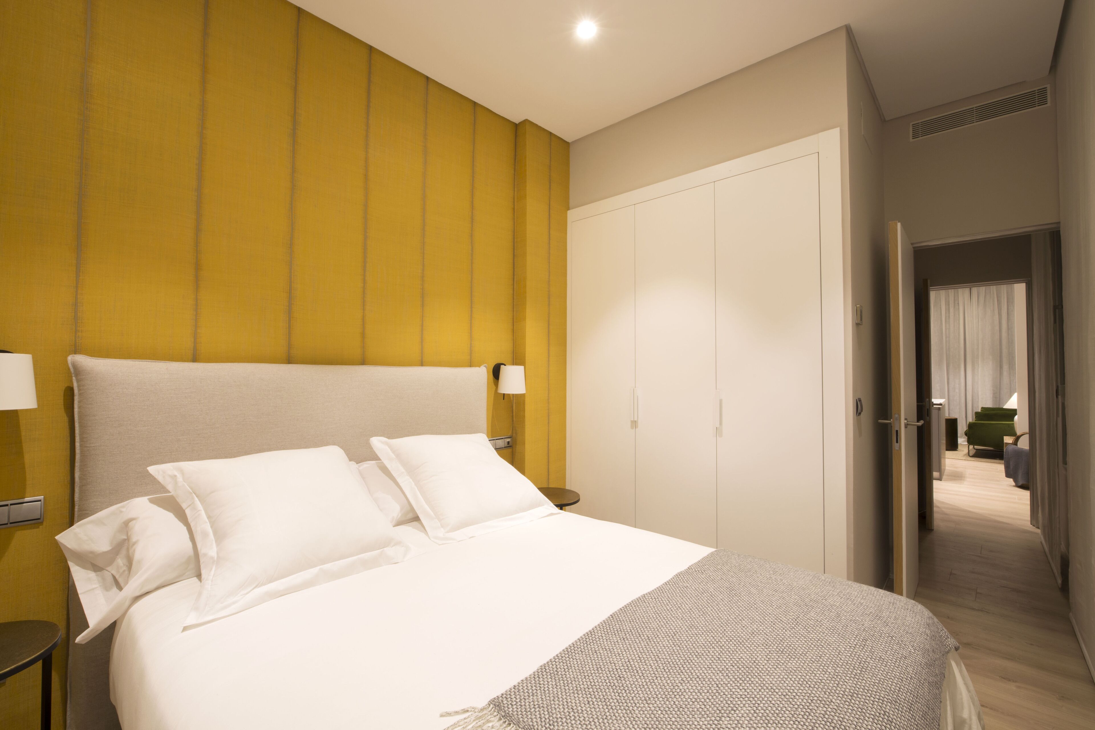 A hotel room with a large bed, a wardrobe, and a small table.