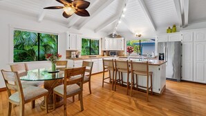 A spacious kitchen with white cabinetry, a central island, and a ceiling fan.