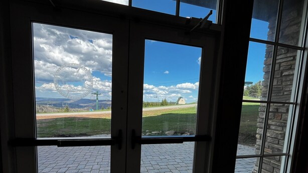 Vista a través de una ventana que muestra un muro de piedra y un patio empedrado.