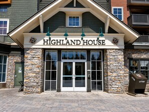 A building with a stone facade, a sign reading 'HIGHLAND HOUSE', and a trash bin labeled 'LITTER'. - Highland House 302 - Ski-In/Ski-Out! (Snowshoe)