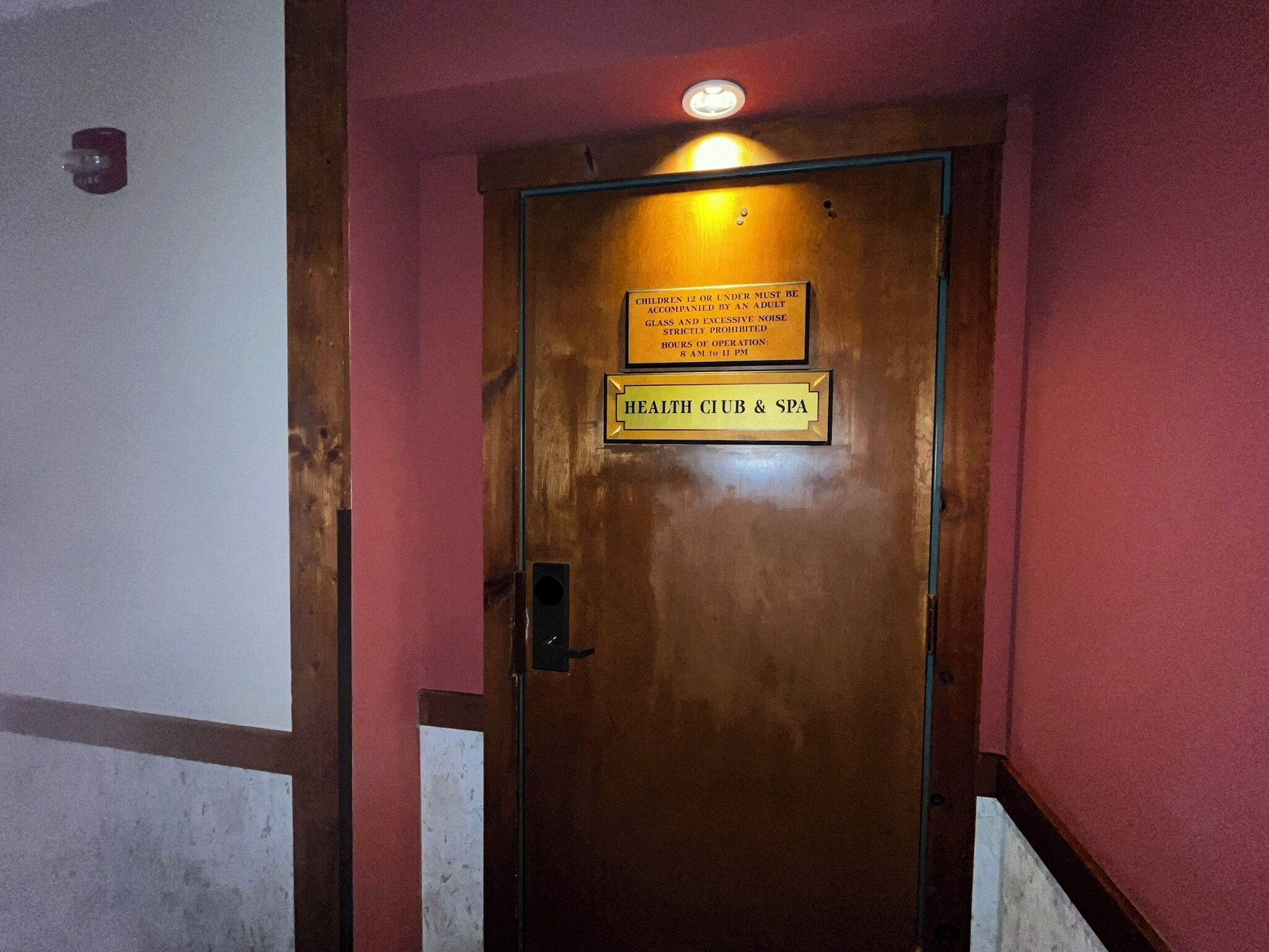 Puerta con un letrero que indica un Club de Salud y Spa, con horario de atención de las 8 de la mañana a las 11 de la noche.