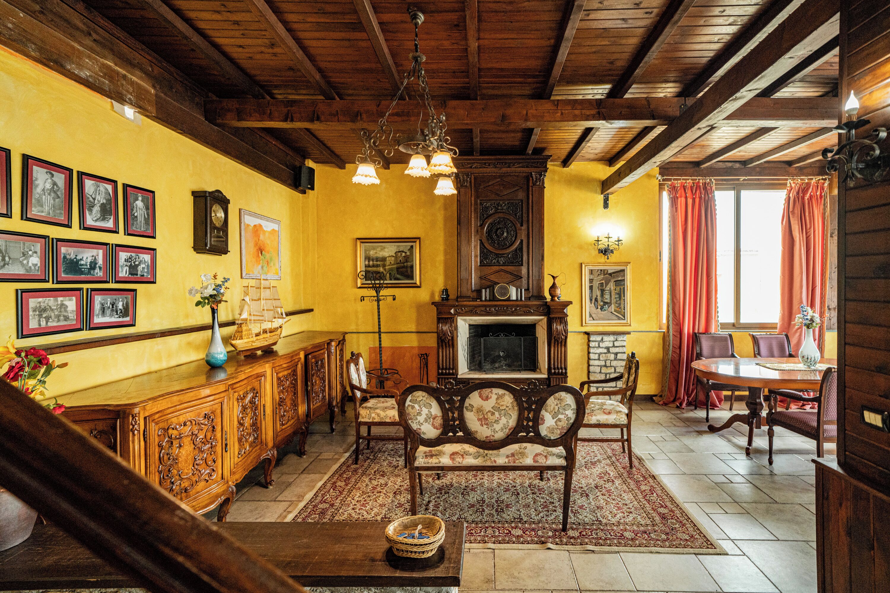 A traditional living room with a wooden ceiling, a fireplace, a dining table, and a sofa.