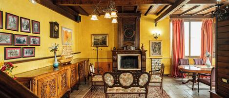 A traditional living room with a wooden ceiling, a fireplace, a dining table, and a sofa.