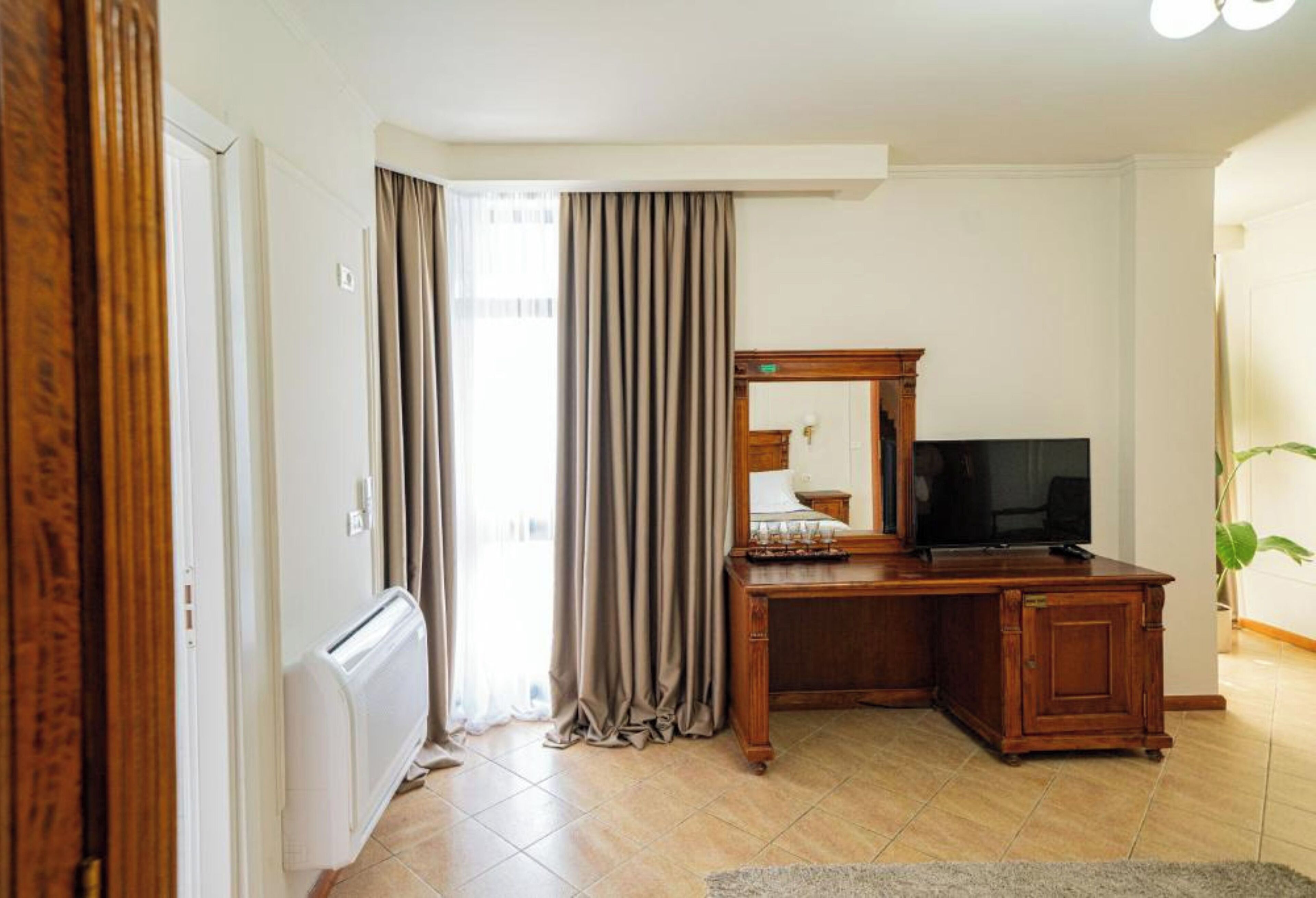 Una habitación con un escritorio de madera, un televisor y un radiador.