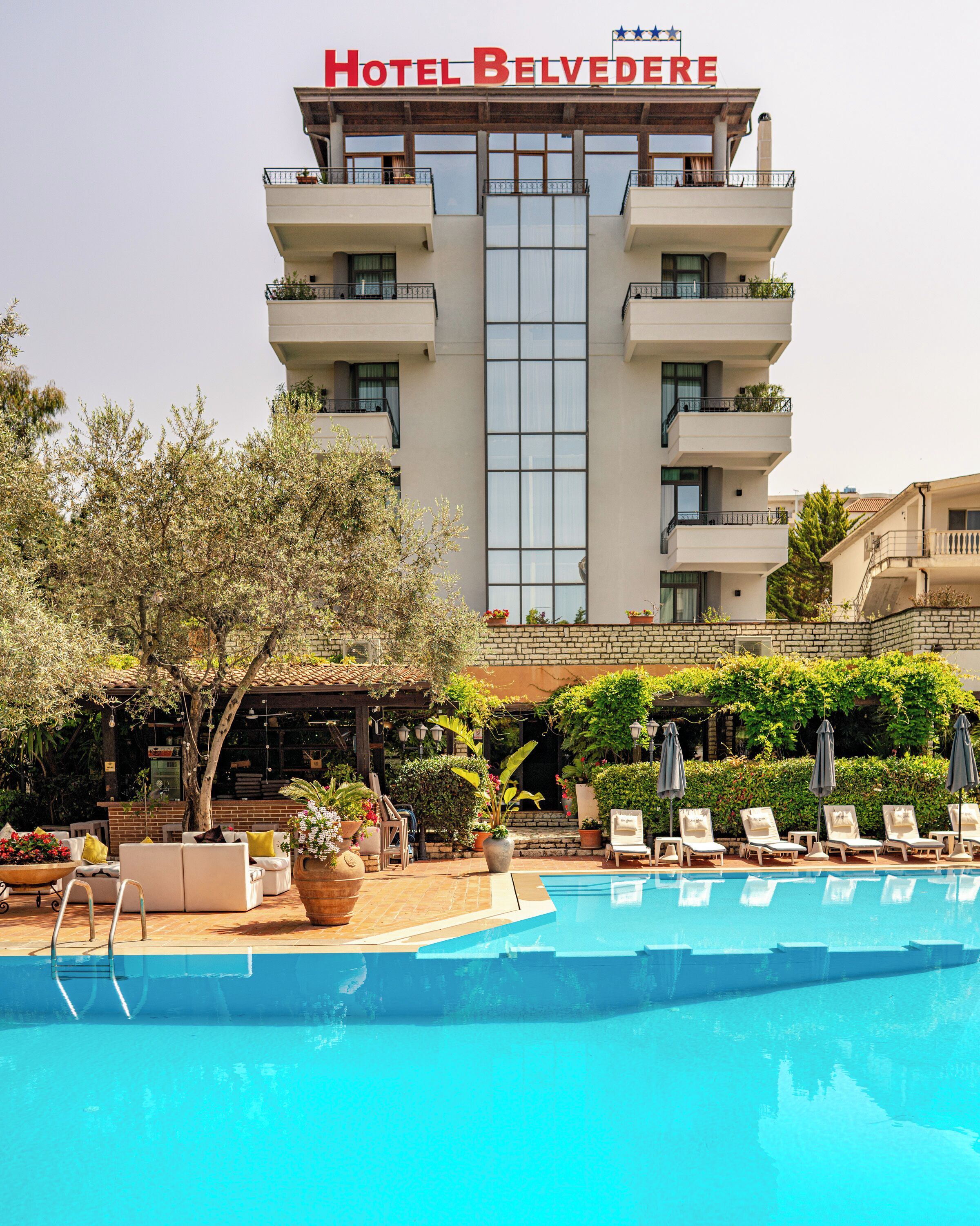Un hotel con piscina, zona de estar al aire libre y un cartel que dice 'Hotel Belvedere'.