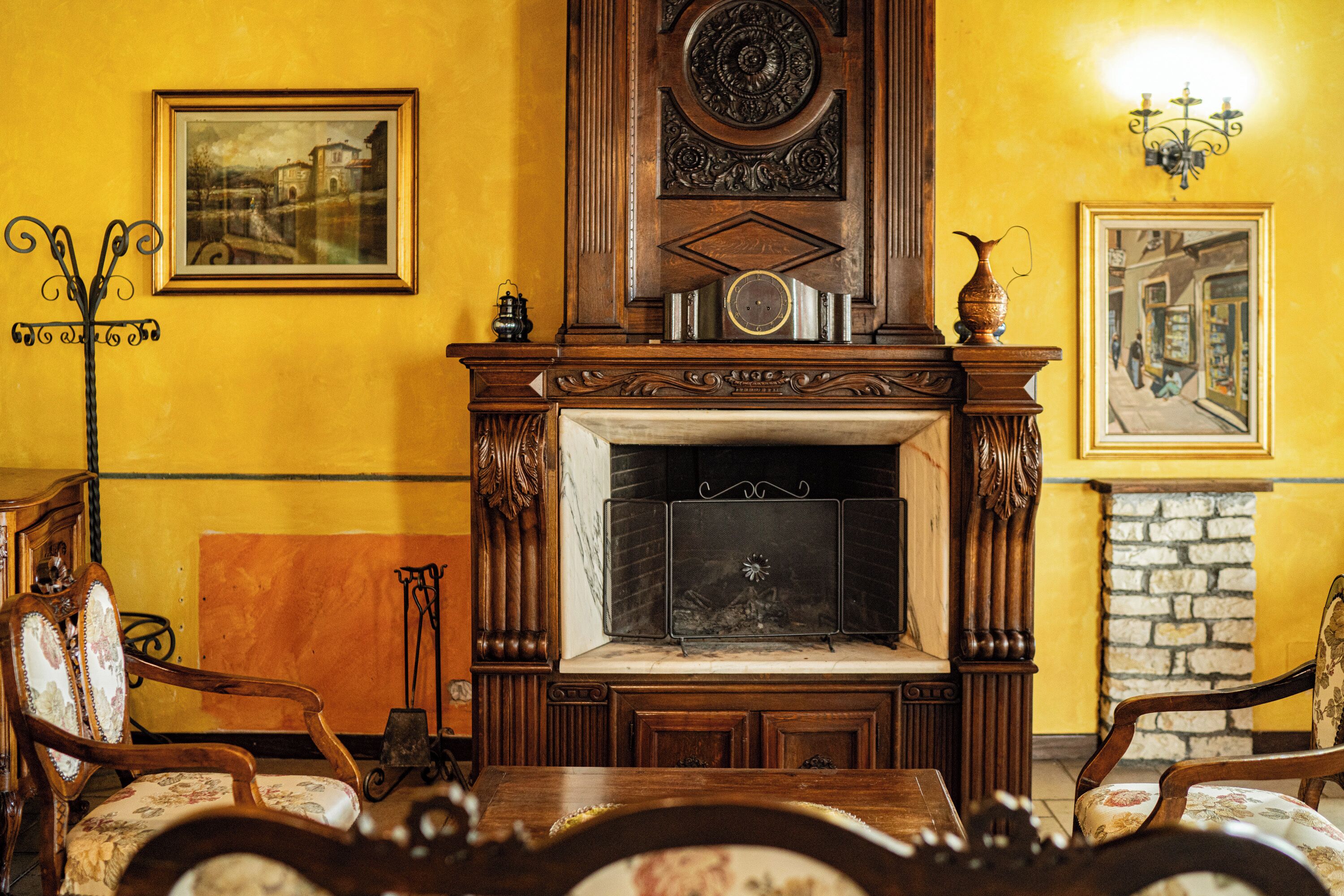 Una habitación tradicional con chimenea, muebles de madera y cuadros en las paredes.