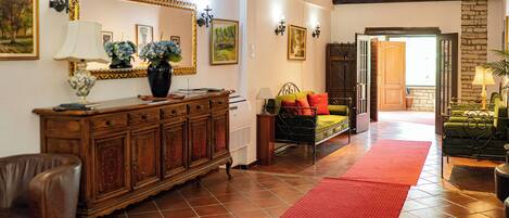 A spacious living area with a wooden cabinet, a sofa, a red rug, and a green armchair.