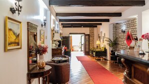 Un amplio vestíbulo de hotel con alfombra roja, muebles de madera y paredes de piedra.