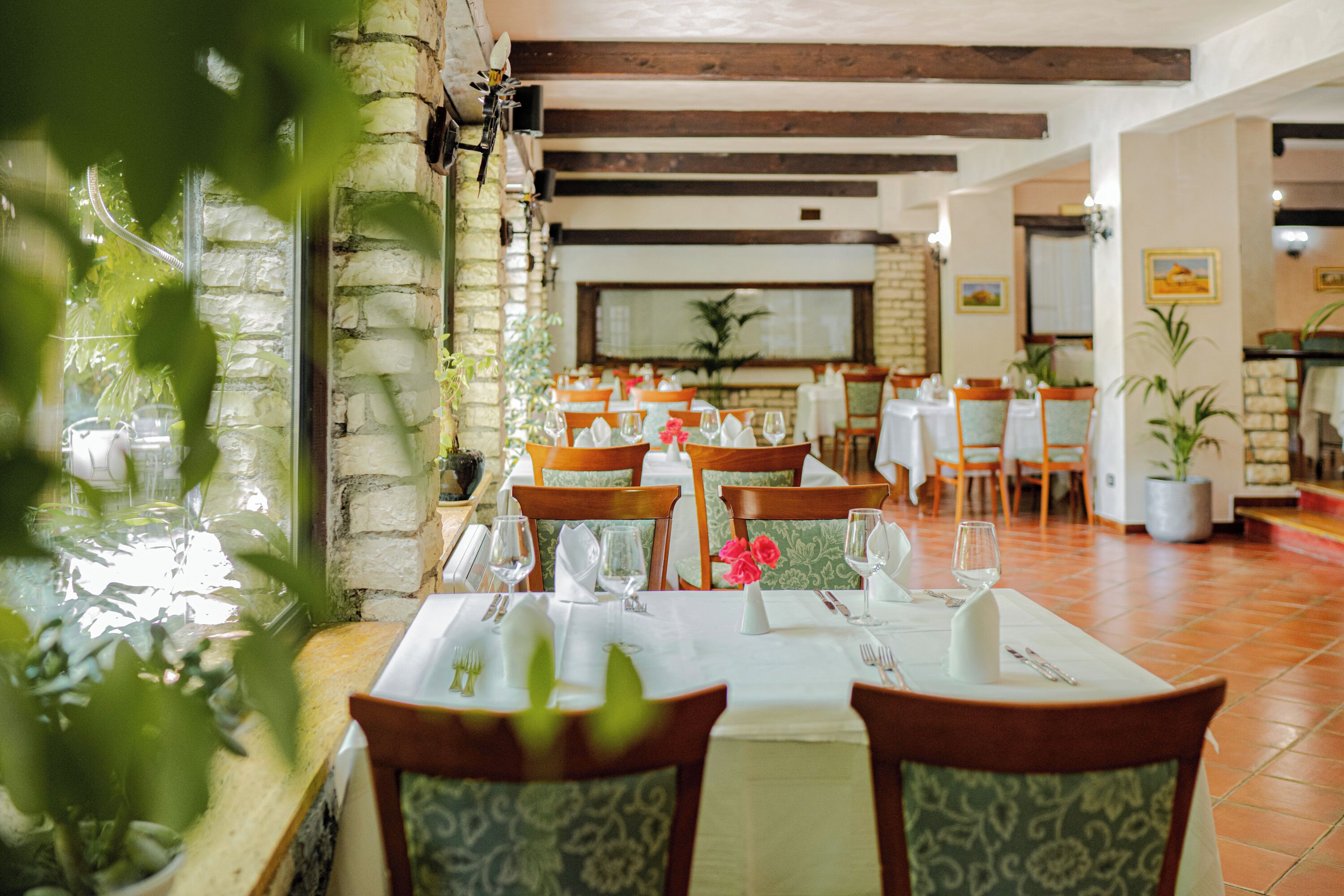 Un restaurante con paredes de piedra, vigas de madera y mesas dispuestas para comer.