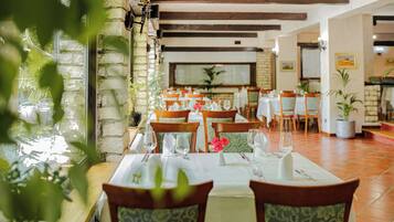 Un restaurante con paredes de piedra, vigas de madera y mesas dispuestas para comer.