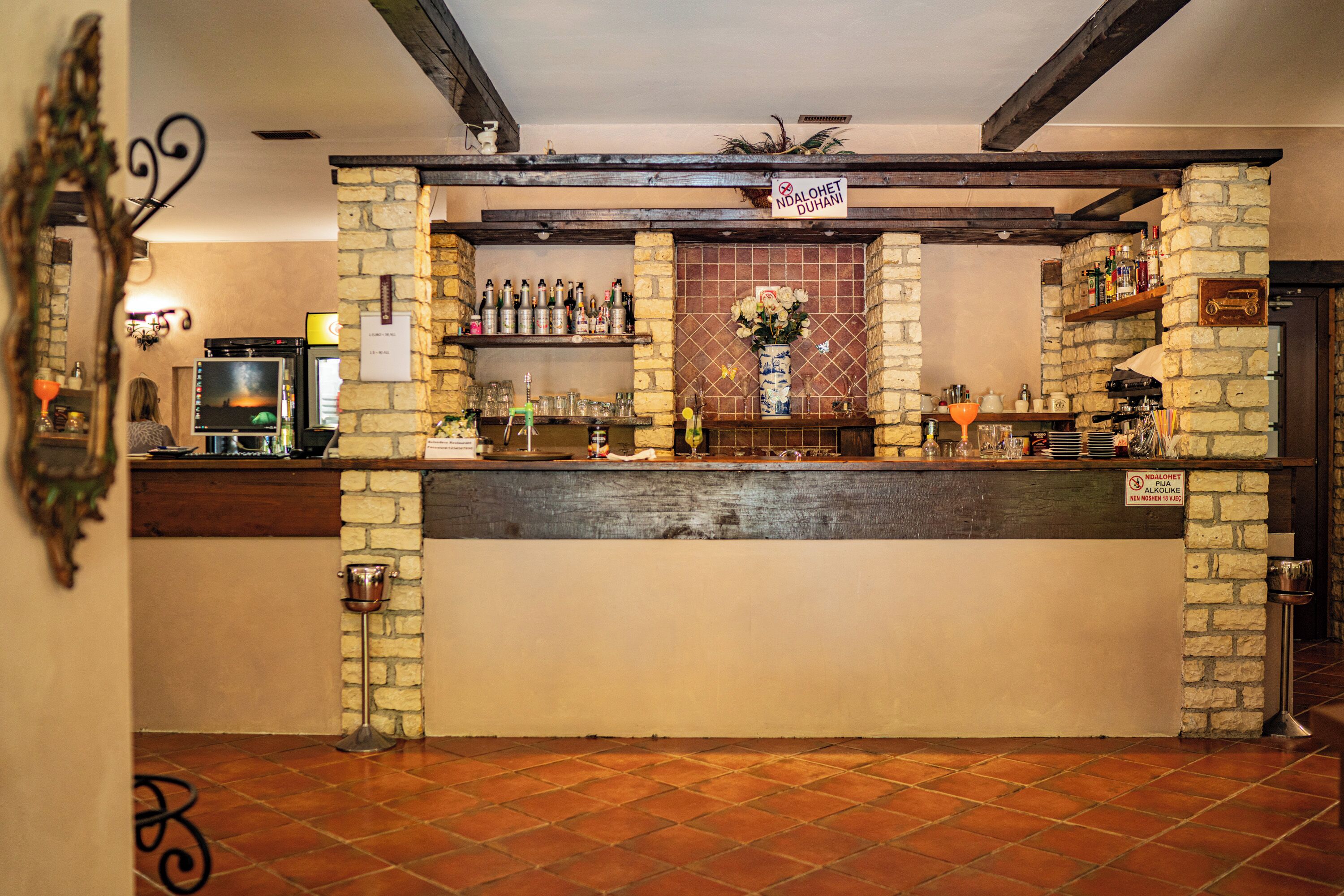 A bar area with a stone wall, wooden beams, and a tiled floor.