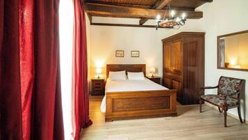 A bedroom with a wooden bed, a nightstand with a lamp, a wardrobe, and a chair.