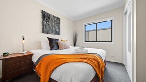 A bedroom with a bed, a bedside table, a lamp, a window, and a painting on the wall. - Jasper 4 in the Town Centre with Lake views (Jindabyne)