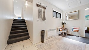 A staircase leading to a landing with a radiator, a small table with chairs, and a mirror on the wall. - Jasper 4 in the Town Centre with Lake views (Jindabyne)