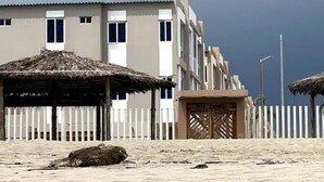A hotel with a thatched-roof structure, a gated entrance, and a sandy beach in the foreground. - Oceanfront Getaway • Nature • Comfort • Gated Community / Frente al Mar (General Villamil Playas)