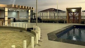A modern outdoor pool area with a clear sky, a street lamp, and a building with a gated entrance. - Oceanfront Getaway • Nature • Comfort • Gated Community / Frente al Mar (General Villamil Playas)