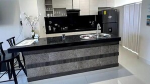 A modern kitchen with a black countertop, stainless steel sink, and white cabinets. - Oceanfront Getaway • Nature • Comfort • Gated Community / Frente al Mar (General Villamil Playas)