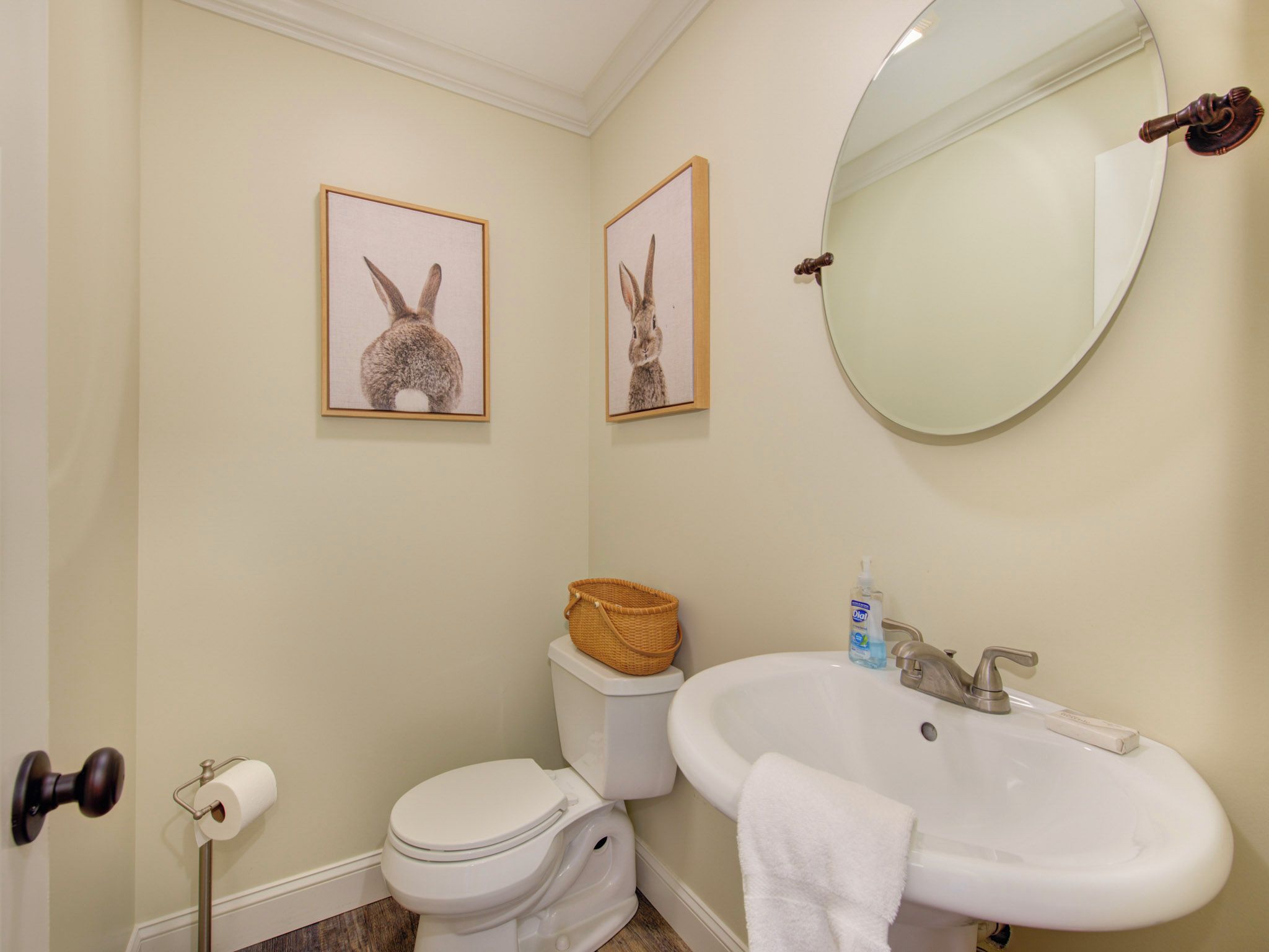 A bathroom with a toilet, sink, and two framed pictures on the wall.