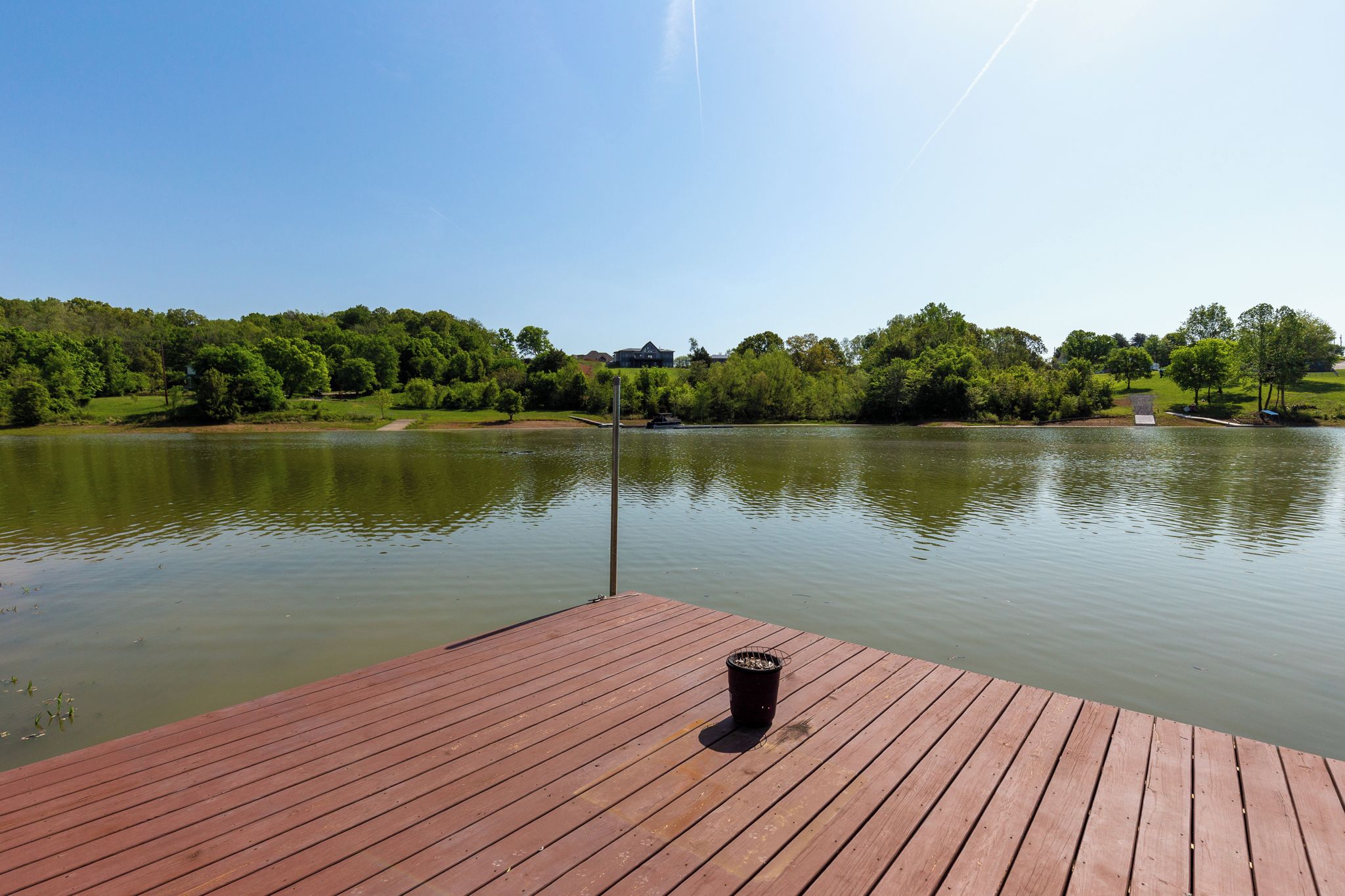 A wooden dock extending over a calm lake with a clear sky.