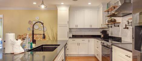 A modern kitchen with white cabinets, stainless steel appliances, and a large island.