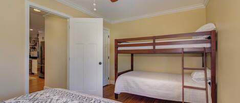 Une chambre avec un lit superposé, un ventilateur de plafond et une couvre-lit à motifs.